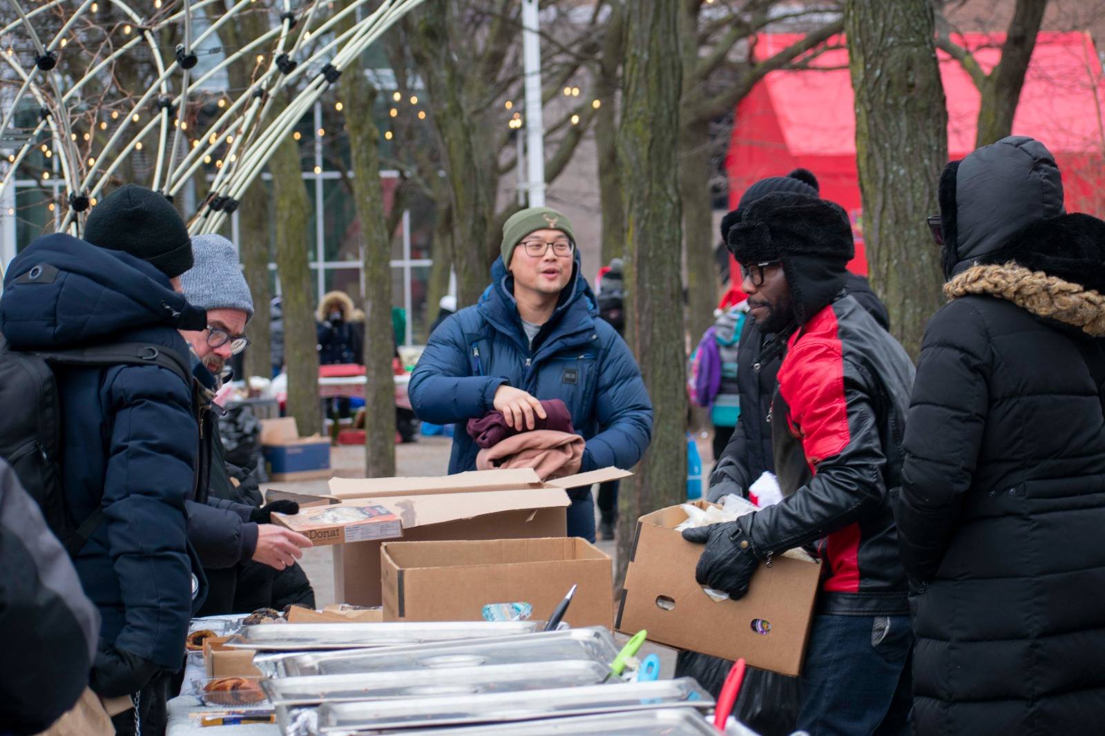 Volunteers sharing food and blankets with community members in Montreal at golden hour